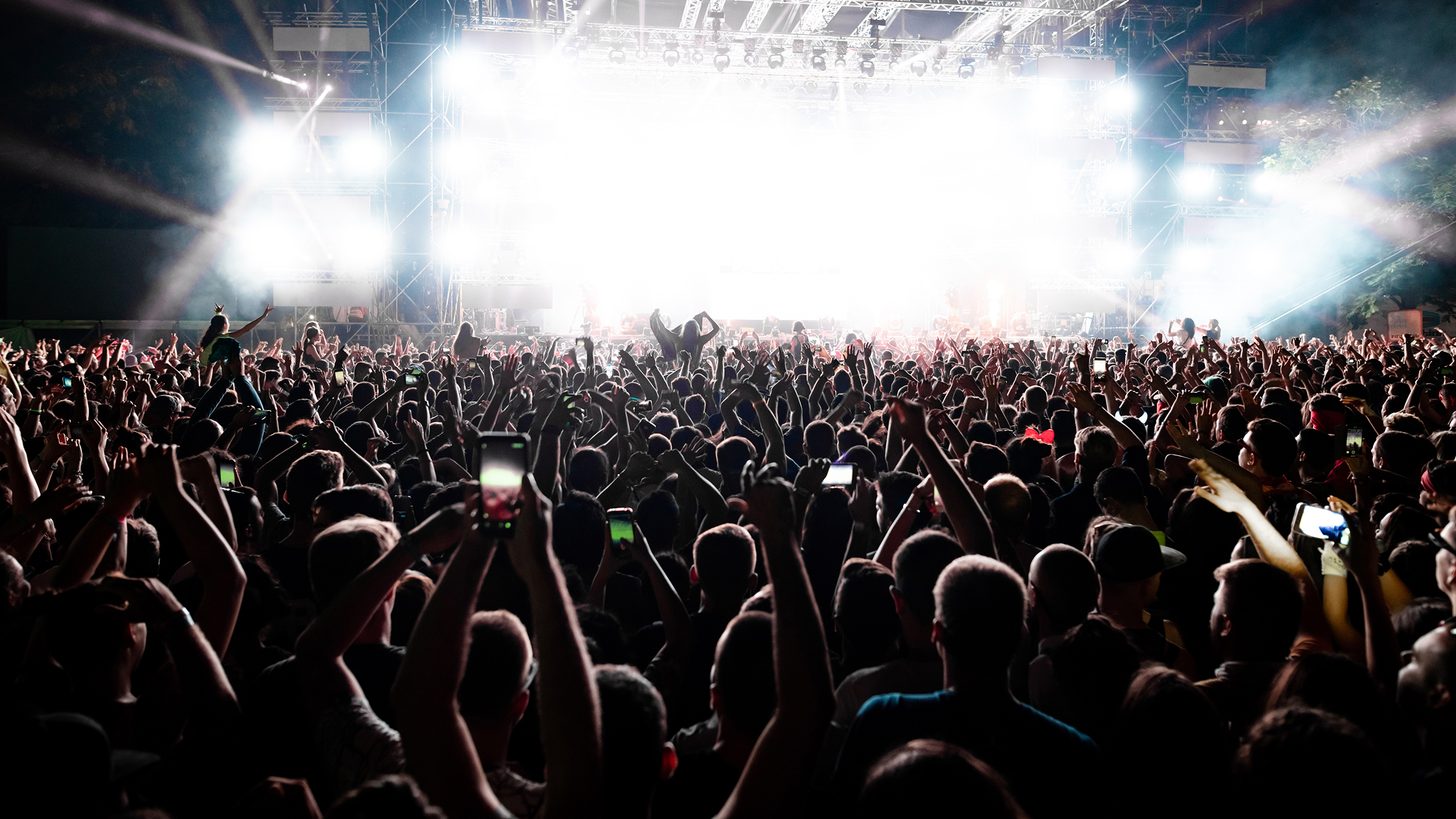 back view excited audience with arms raised cheering front stage music concert copy space